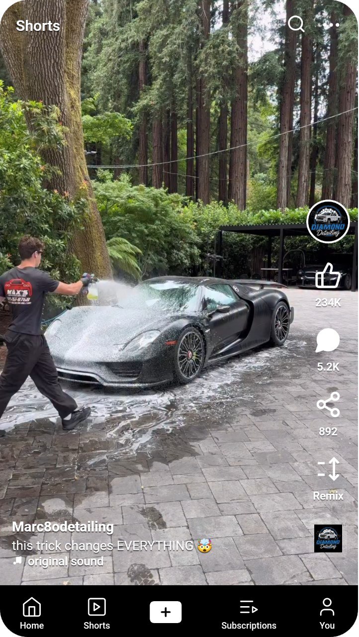 Vertical short of a detailer washing a black sports car, shared as reels content
